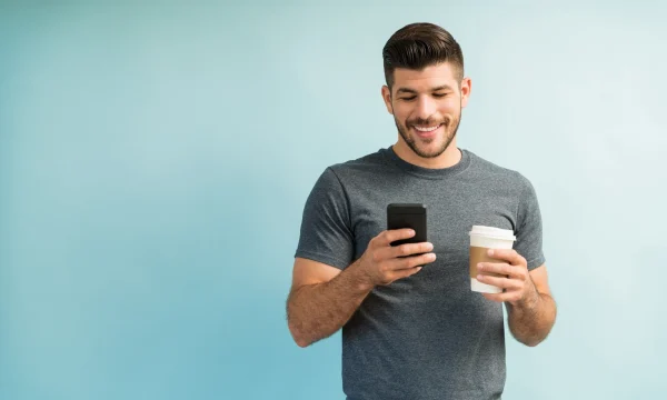 man holding a coffee while using phone