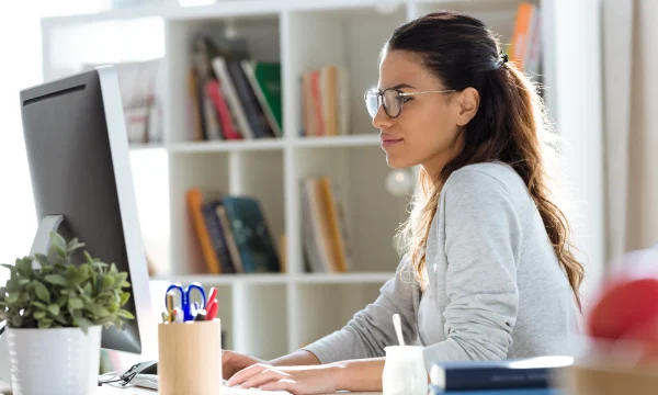 woman in glasses typing on computer